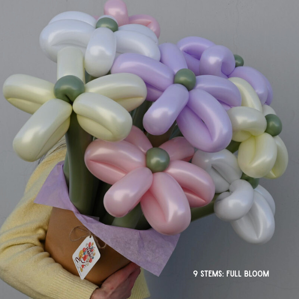 Bouquet of balloon flowers in pastel colors held by a person against a gray background.