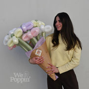 Woman holding a large bouquet of balloon flowers against a plain background